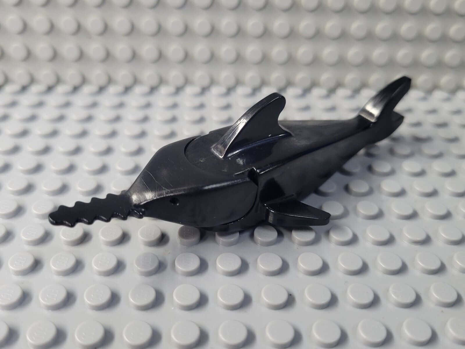  壁紙 — 一個光滑的黑色塑膠海豚LEGO積木放在帶有凸點紋理的白色LEGO底板上。