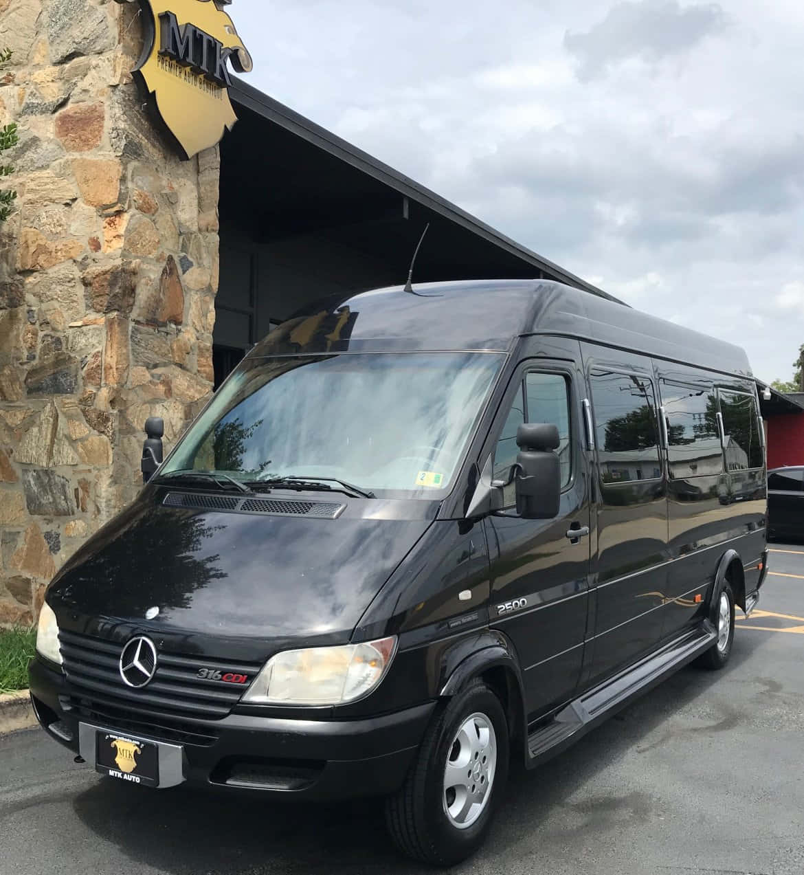 Mercedes Benz Sprinter 桌布 壁紙 — 一輛時尚的黑色 Mercedes-Benz Sprinter 客貨車停放在石建築物外，天空多雲。