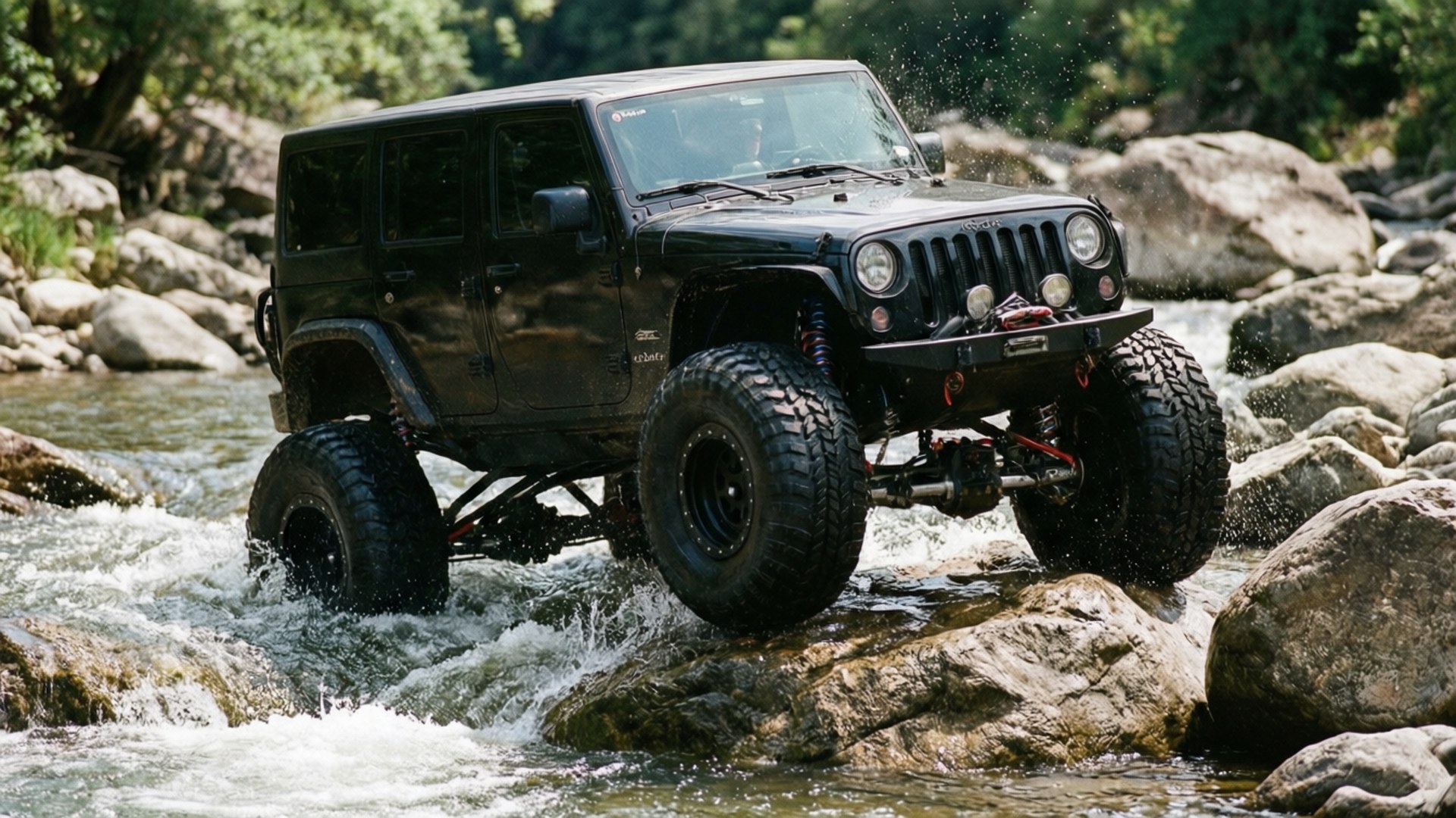 Rock Crawling Action 壁紙 — 一輛黑色升高的Jeep Wrangler配備超大輪胎，在岩石河床上行駛濺起水花。