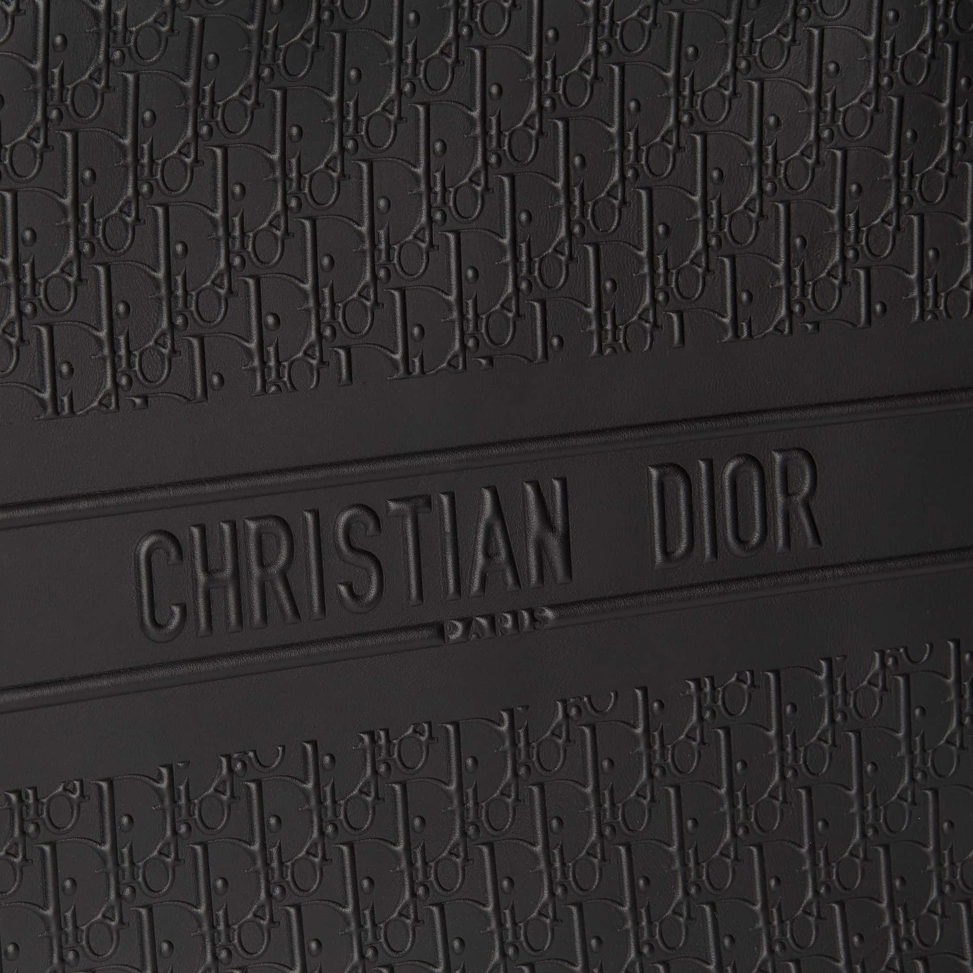  壁紙 — 黑色紋理皮革特寫，帶有重複的Dior字母組合和浮雕Christian Dior Paris品牌標誌。