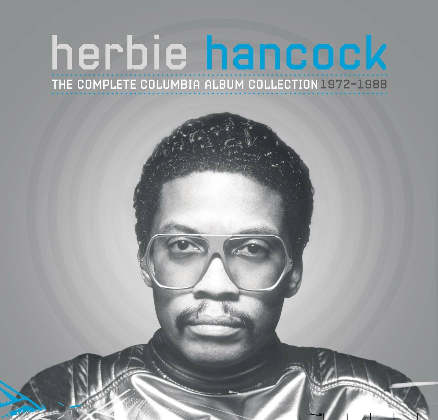 音樂 桌布 壁紙 — Herbie Hancock 的黑白肖像，戴著大眼鏡和閃亮外套，背景為灰色圓形。
