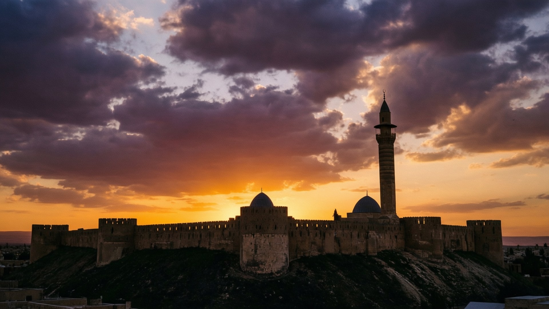 Saladin Citadel Sunset 壁紙 — 一座歷史悠久的堡壘，擁有圓頂結構和高聳的宣禮塔，在充滿紫色和橙色雲彩的 vibrant 日落天空下呈現剪影。
