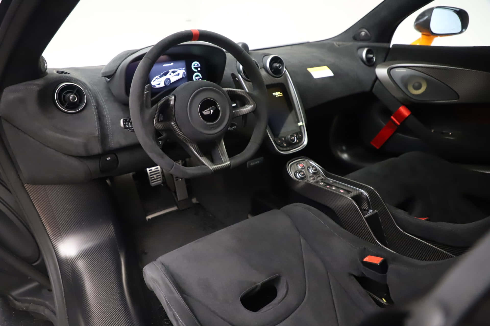 Mclaren 620r 桌布 壁紙 — 豪華跑車內裝，帶有黑色碳纖維飾邊和紅色安全帶。