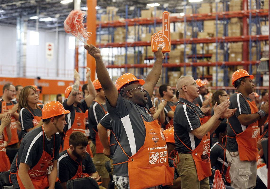 Home Depot 桌布 壁紙 — Home Depot 員工戴上橘色頭盔和圍裙，在一個充滿產品貨架的大型倉庫中，熱情地揮舞著泡棉手指歡呼。