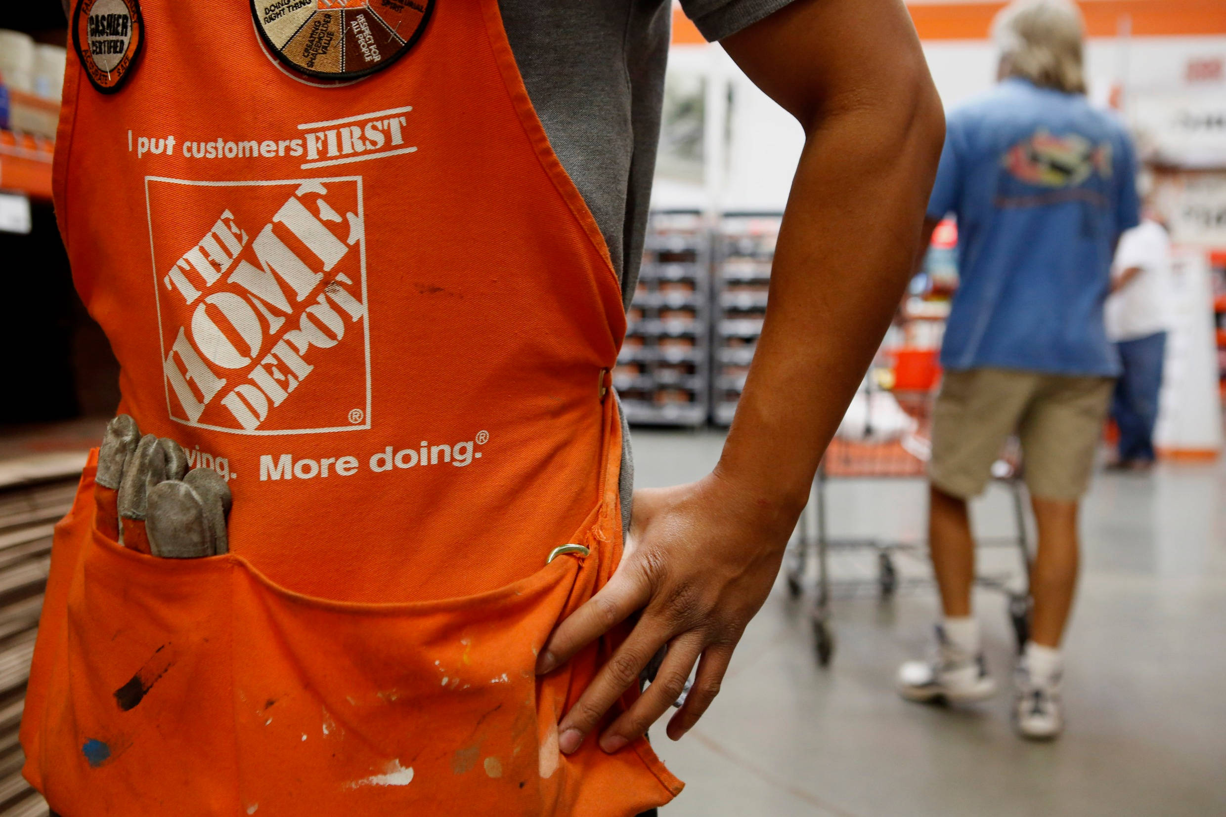 Home Depot 桌布 壁紙 — Home Depot 員工身穿橙色圍裙，口袋裡放著工具，站在五金店通道的特寫。