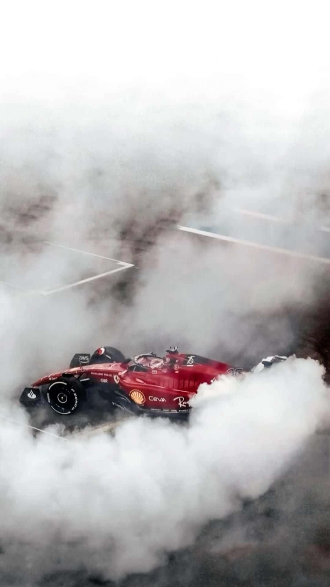 紅色賽車在賽道上穿過濃厚煙霧飛馳。 — F1 壁紙