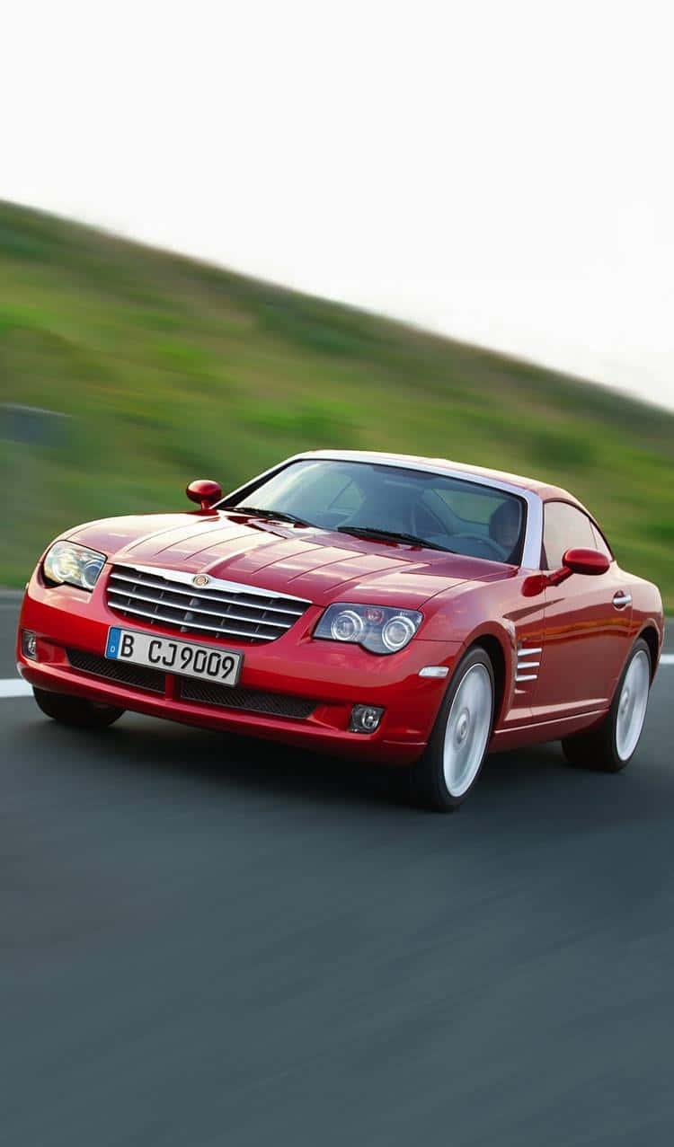 Chrysler Crossfire 桌布 壁紙 — 一輛充滿活力的紅色敞篷跑車在蜿蜒的道路上奔馳，背景是模糊的綠色山丘。