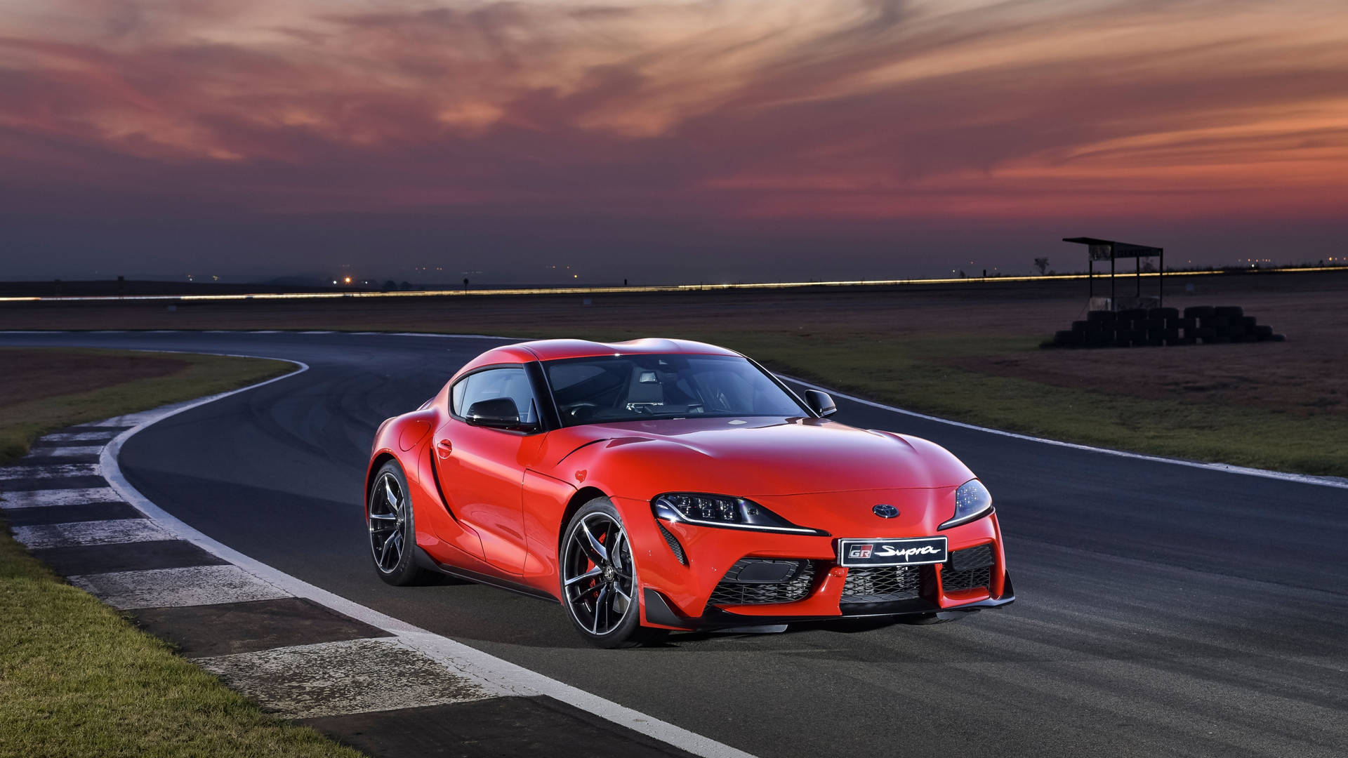 紅色豐田Supra在日落時分的賽道上疾馳。 — Toyota Supra 壁紙