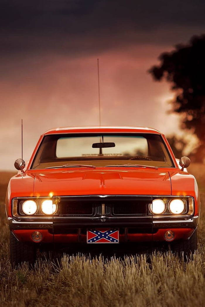 紅色經典肌肉車在黃昏時分停在草地上，車頭燈亮著。 — General Lee 車 壁紙