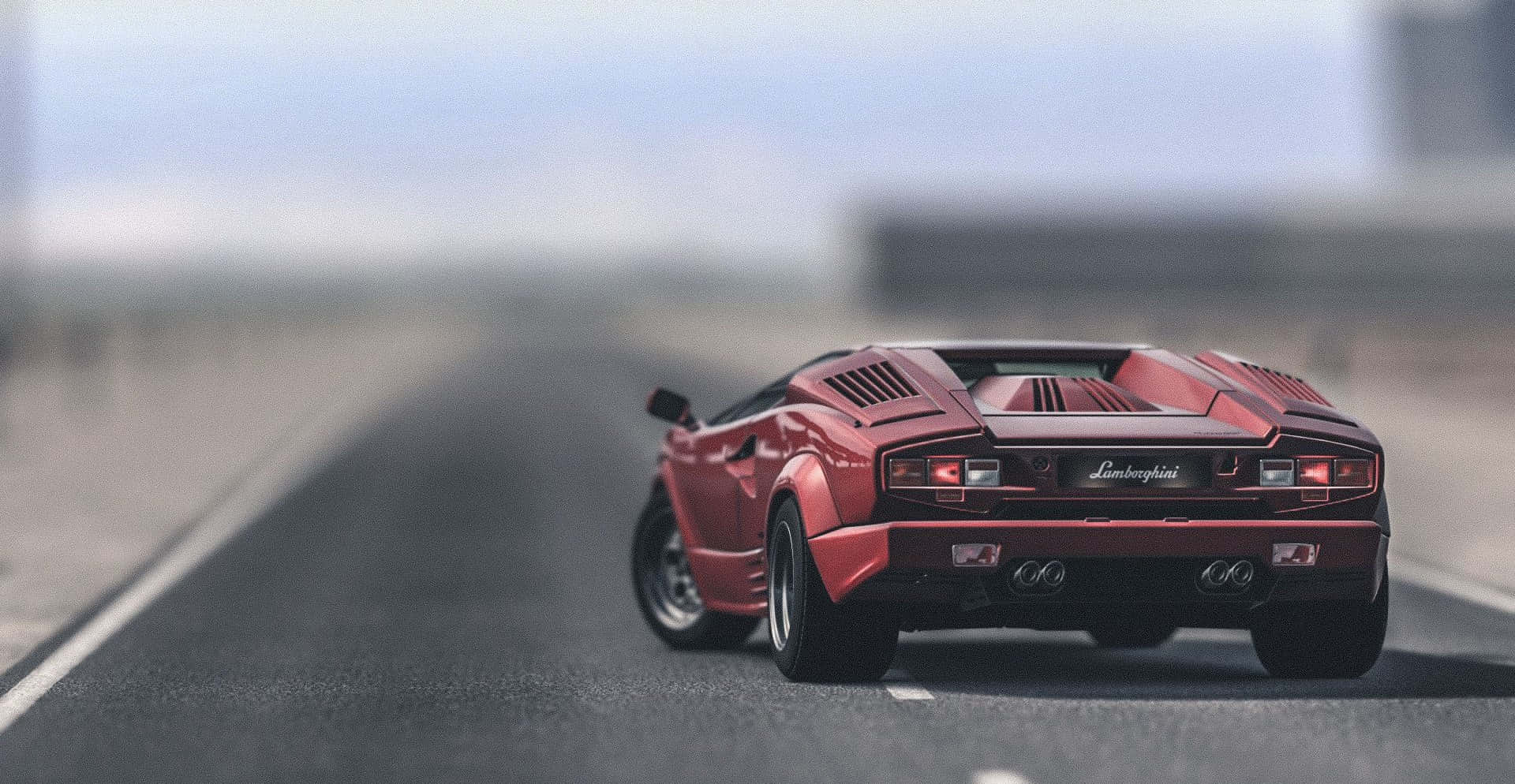 Lamborghini Countach 桌布 壁紙 — 一輛紅色藍寶堅尼跑車在模糊的高速公路上行駛，天空朦朧。