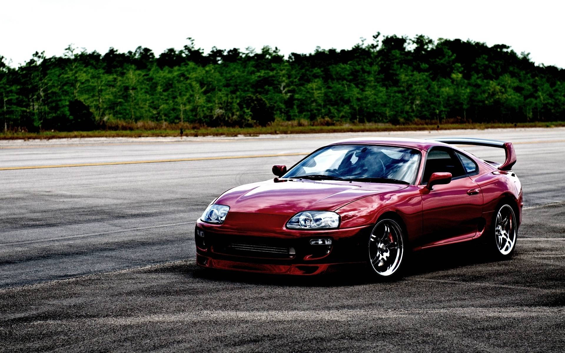 紅色跑車在空曠賽道上，背景為森林 — Toyota Supra 壁紙