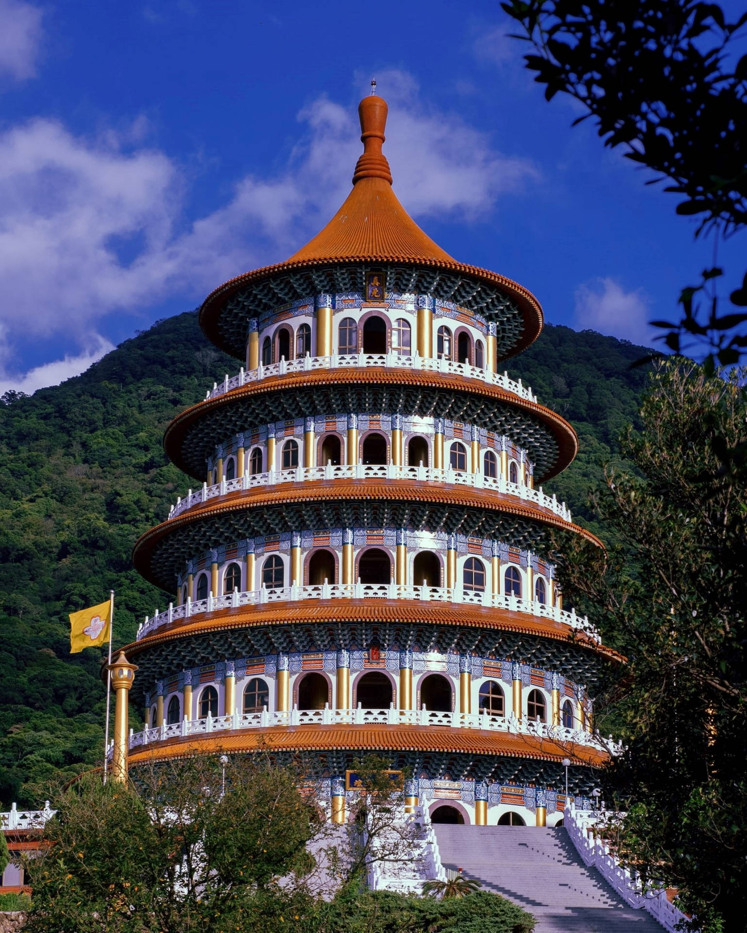 宏偉的多層寺廟，橙色屋頂，坐落在藍天下的綠色山巒中。 — 台北 壁紙