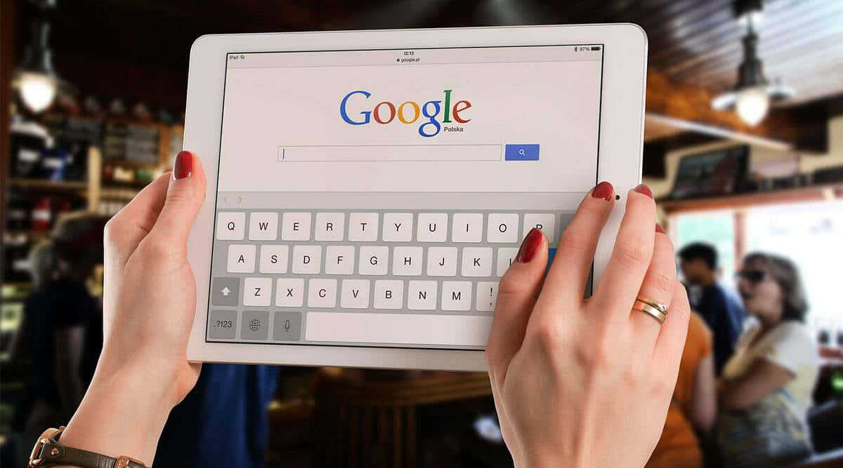 在咖啡店使用平板電腦搜尋Google的人。 — Google 壁紙