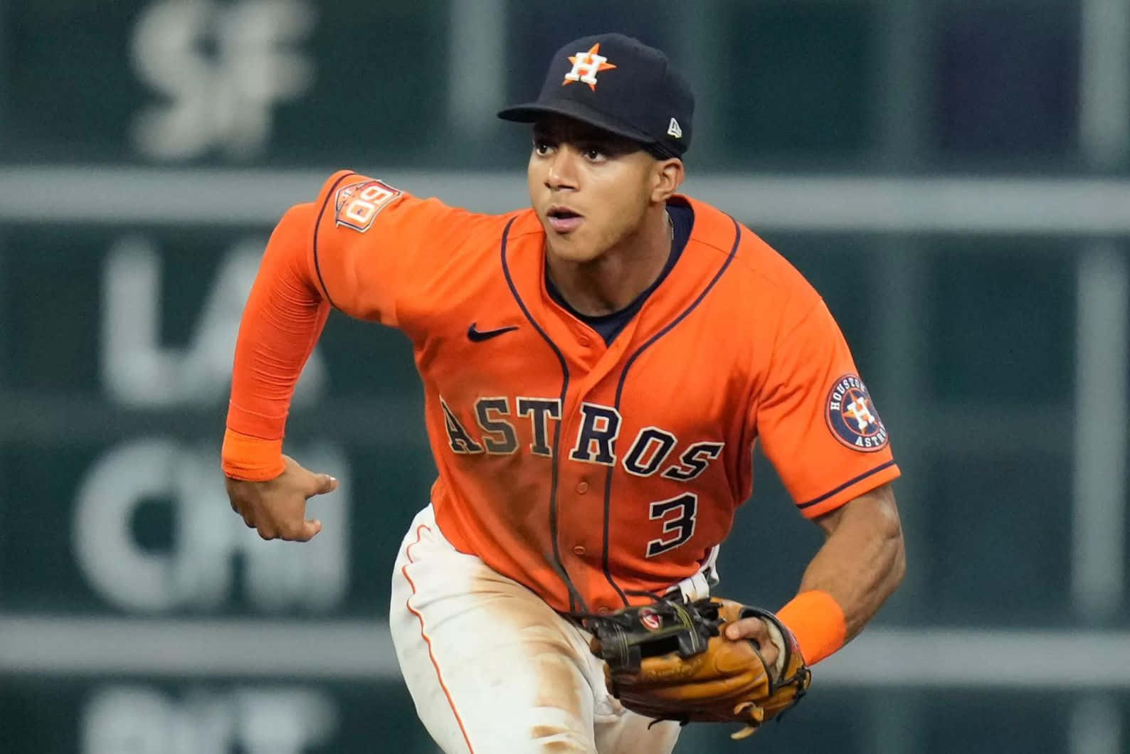  壁紙 — 一位身穿橙色球衣的休士頓太空人棒球選手在夜間比賽中專注地衝刺。