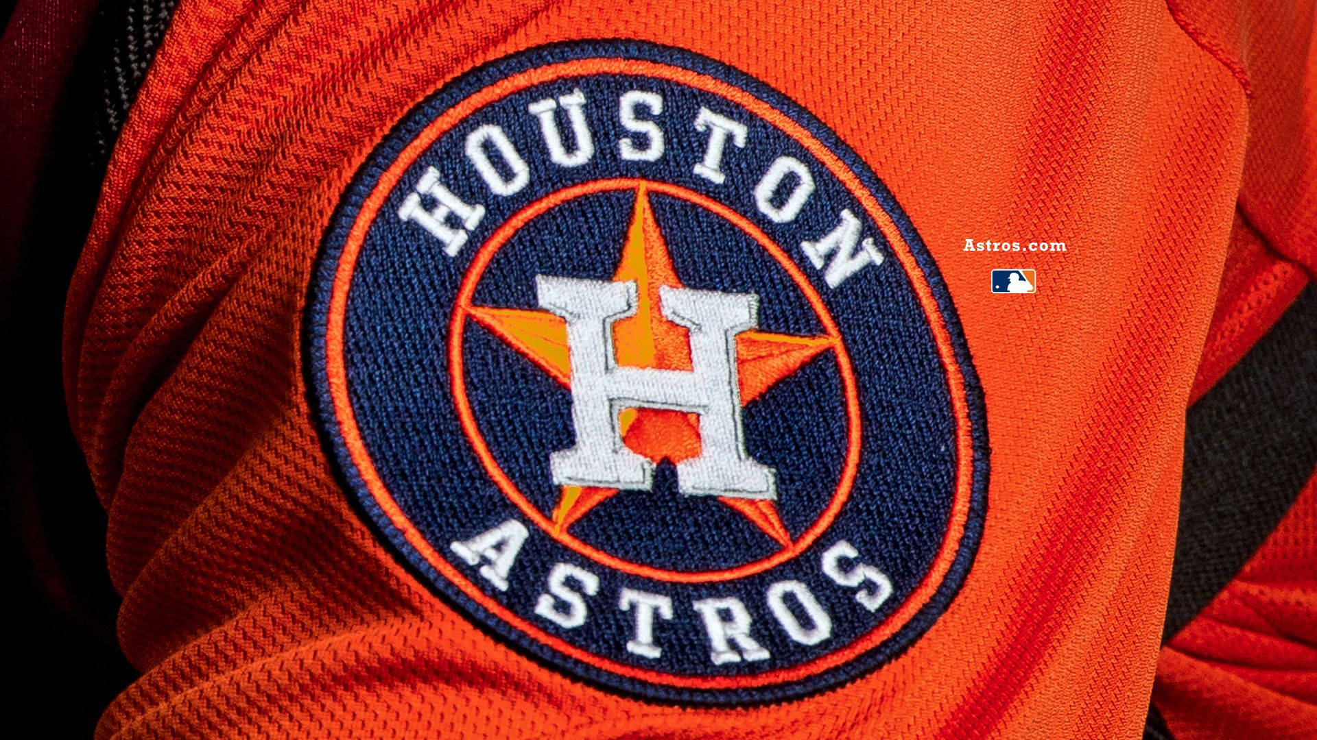 Astros 桌布 壁紙 — Houston Astros 棒球球衣標誌的特寫，繡在充滿活力的橙色布料上。