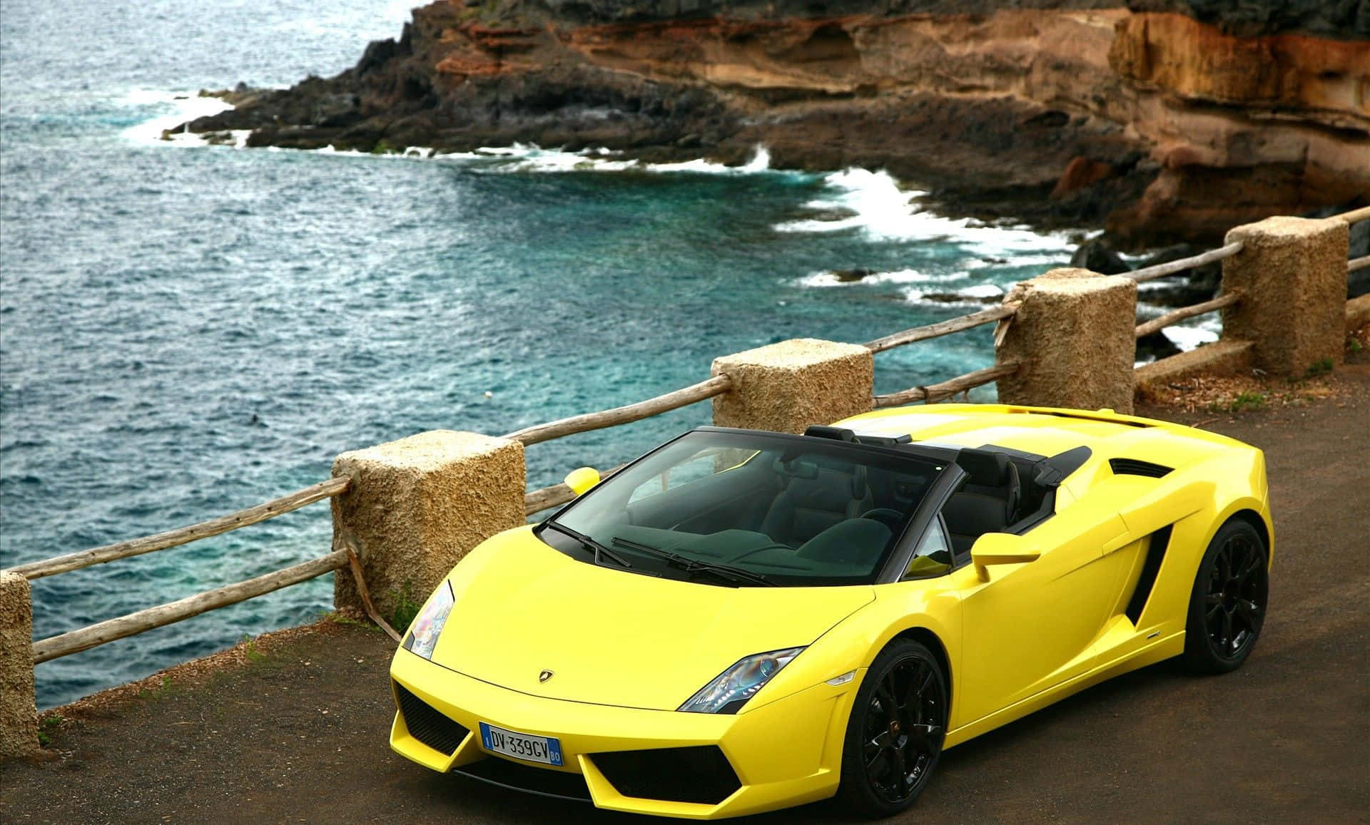 Lamborghini Murciélago 桌布 壁紙 — 一輛亮黃色的藍寶堅尼Gallardo Spyder停泊在海岸懸崖上，俯瞰著碧綠色的海浪。