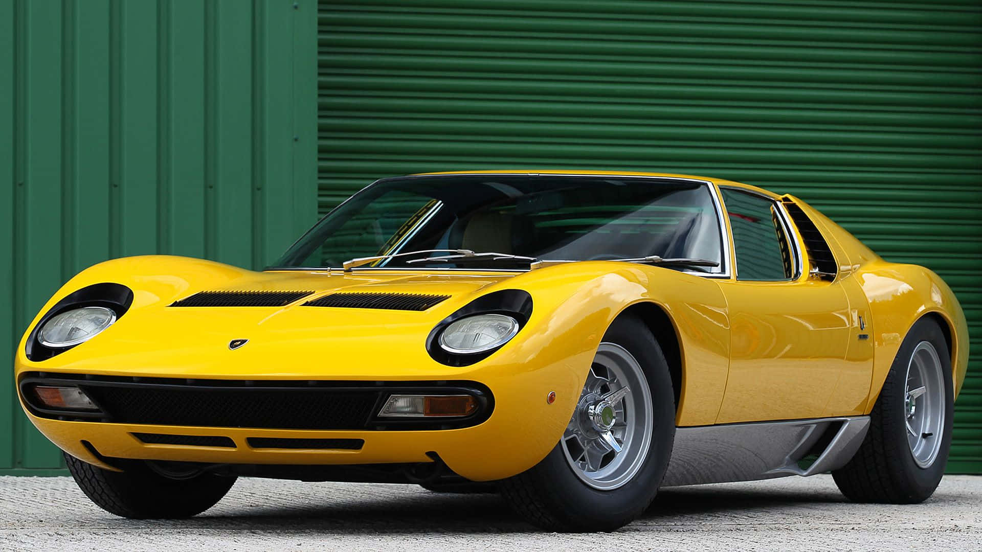 Lamborghini Miura 桌布 壁紙 — 一輛充滿活力的黃色藍寶堅尼Miura跑車在日光下閃閃發光，背景是綠色波紋金屬板。