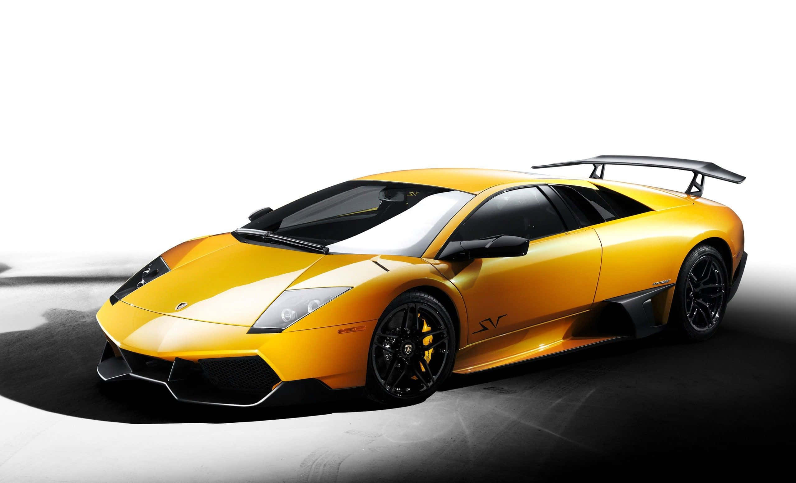 Lamborghini Murciélago 桌布 壁紙 — 一輛鮮黃色的藍寶堅尼跑車，帶有黑色飾件和後擾流板，在黑白攝影棚背景下戲劇性地擺放。