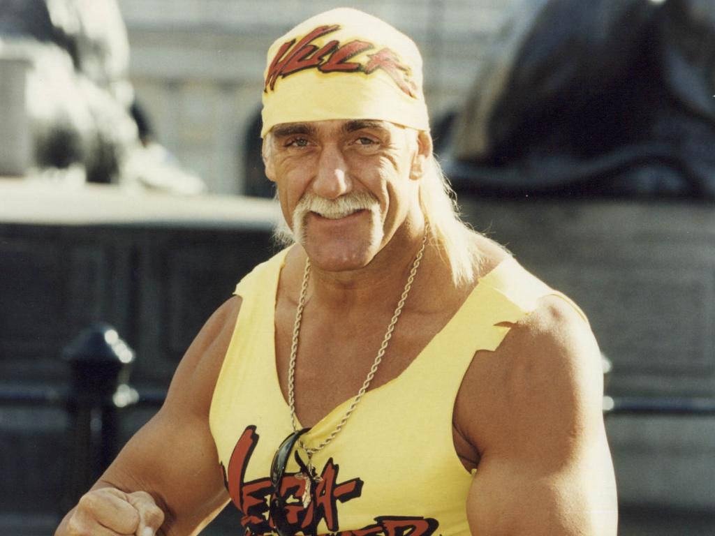 Hulk Hogan 桌布 壁紙 — Hulk Hogan 身穿標誌性黃色摔角裝備，帶著招牌鬍子和頭帶，自信地微笑。