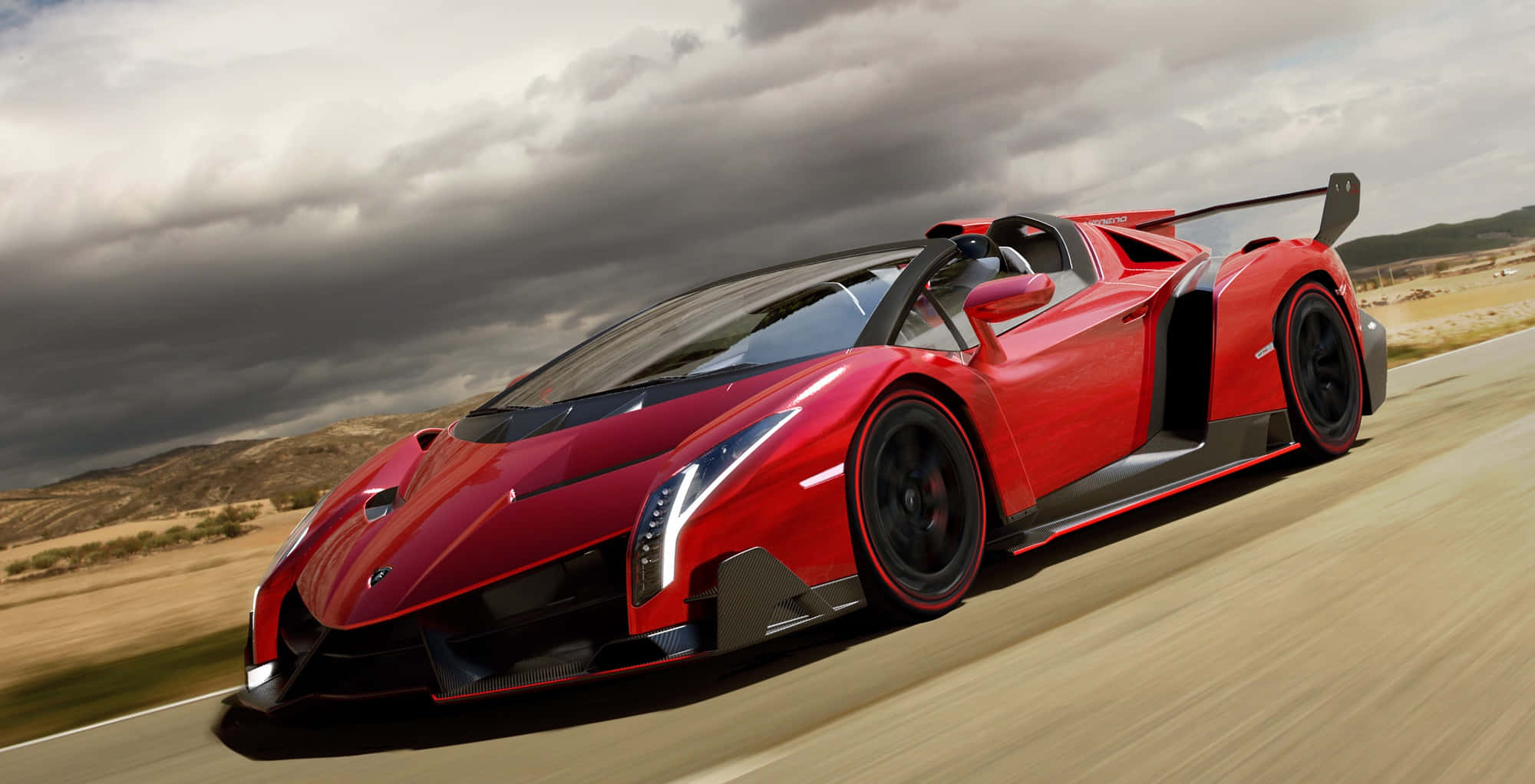 Lamborghini Veneno 桌布 壁紙 — 一輛鮮紅色的藍寶堅尼 Veneno 在戲劇性的多雲天空下，沿沙漠公路飛馳。