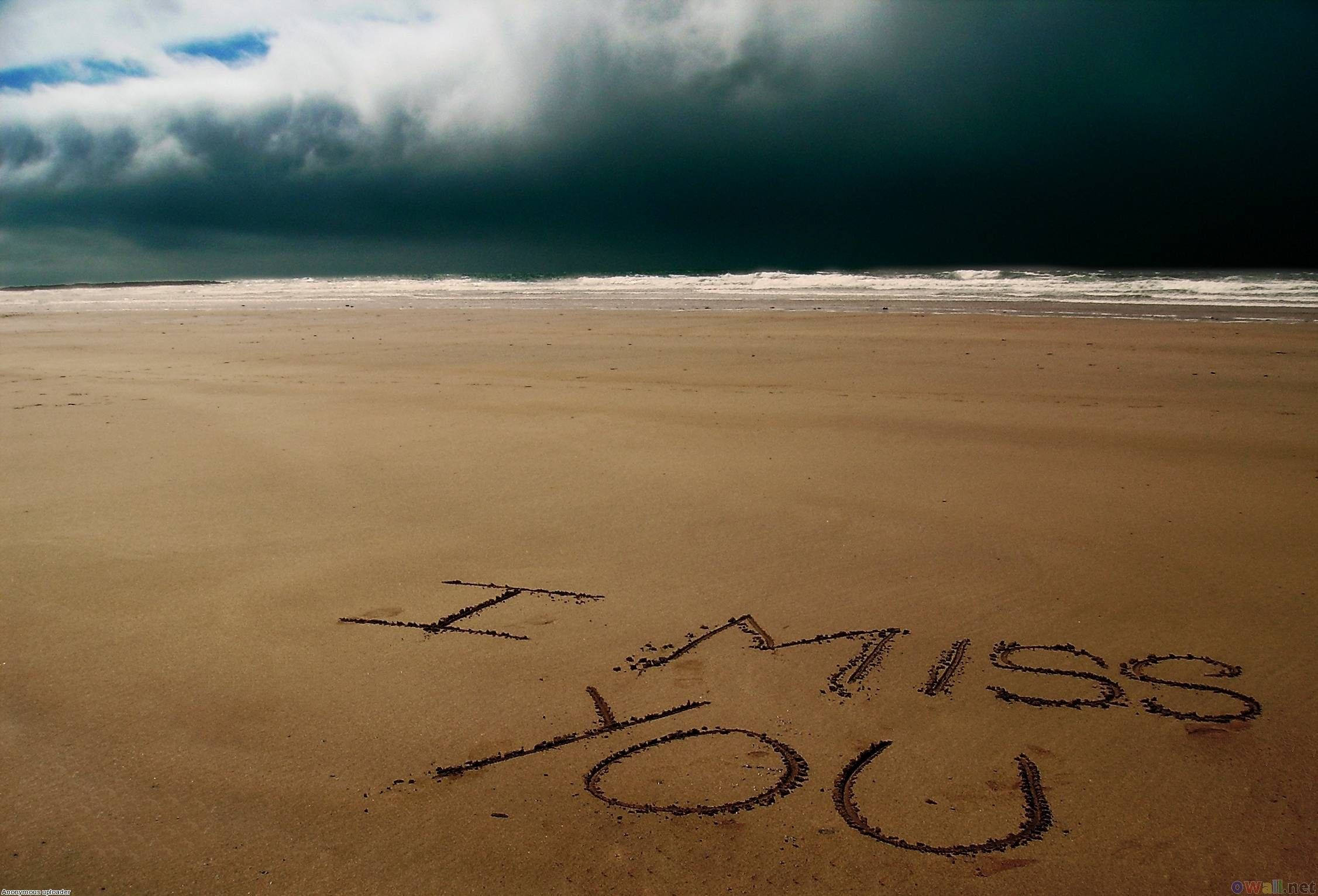 我想你 桌布 壁紙 — 「I MISS YOU」這幾個字刻在廣闊沙灘的濕沙上，而黑暗的暴風雲籠罩著海洋。
