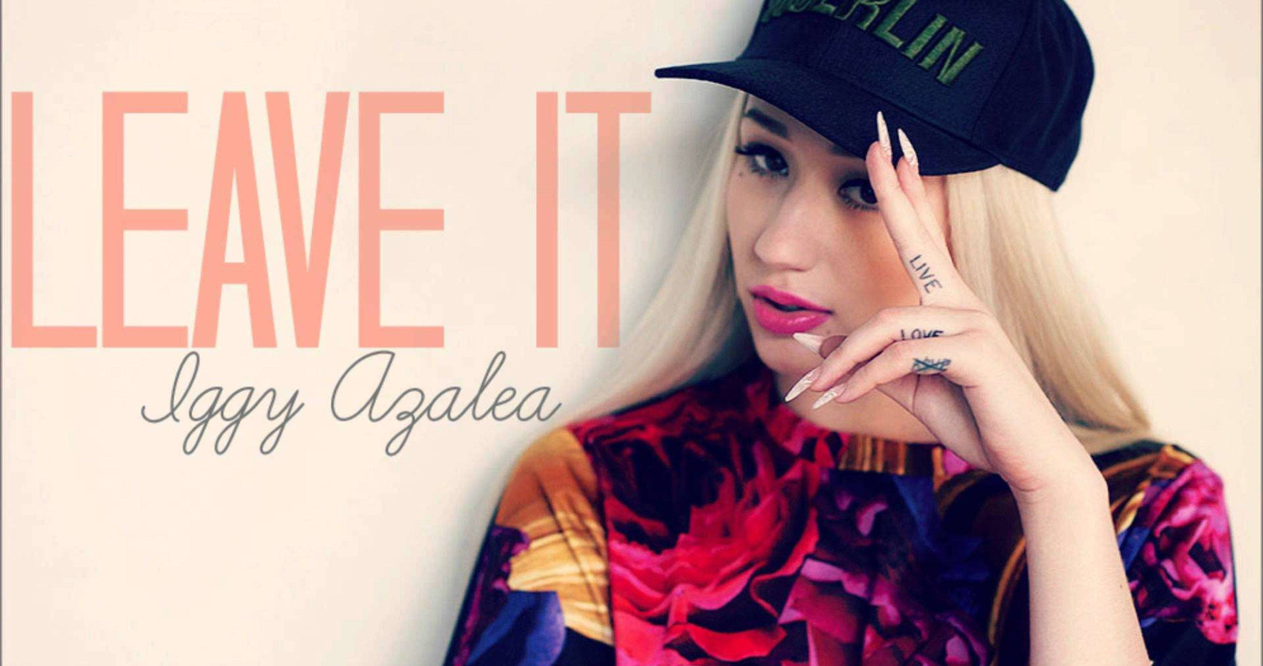 說唱歌手 桌布 壁紙 — Iggy Azalea 自信地擺姿勢，身穿彩色花卉上衣和黑色帽子，背景是素牆，上面有粗體的桃色文字寫著「LEAVE IT」。
