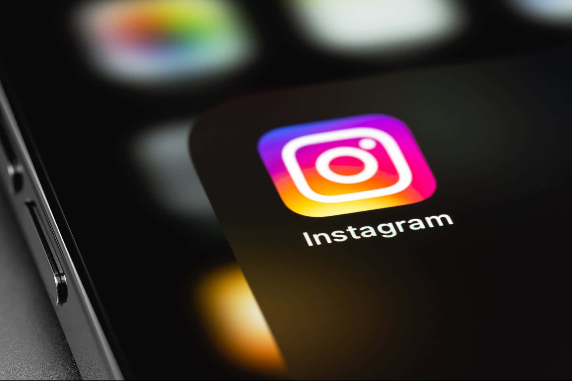 Instagram 桌布 壁紙 — Instagram應用程式圖標在智慧型手機螢幕上發光的特寫，背景應用程式模糊。