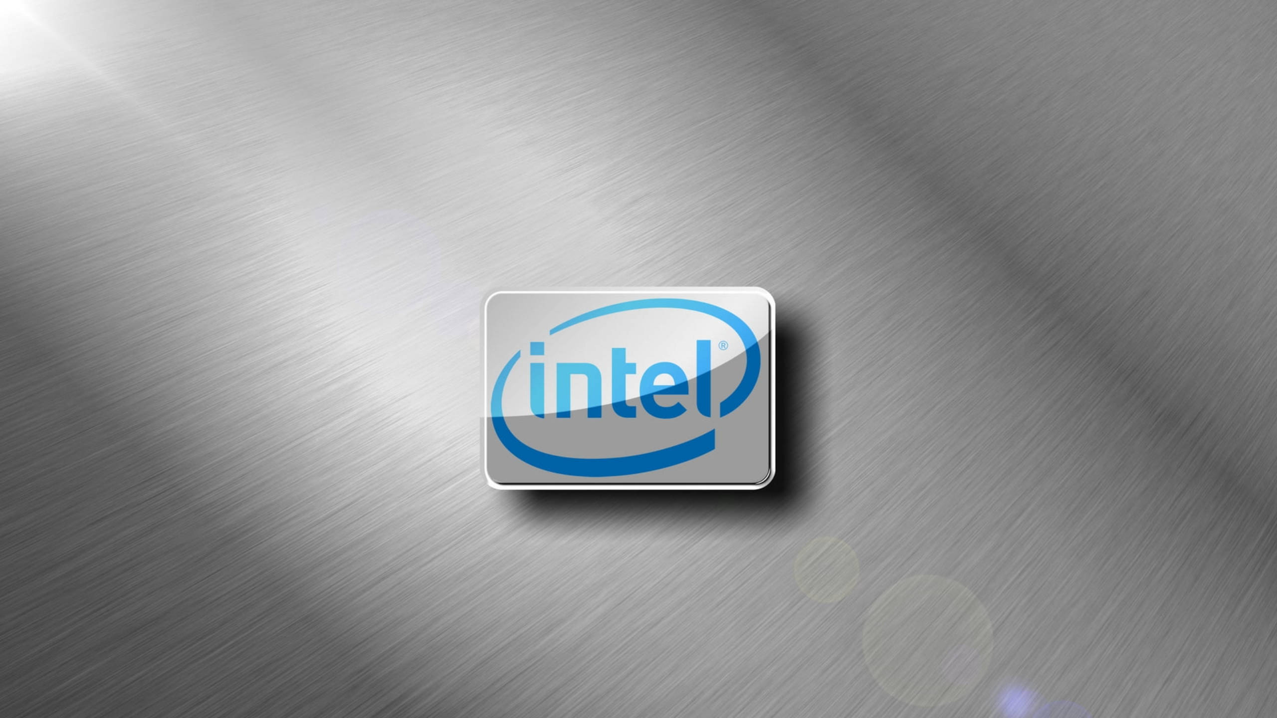 Silver 桌布 壁紙 — Intel 標誌居中於拉絲金屬表面，帶柔和鏡頭光暈和漸變照明。