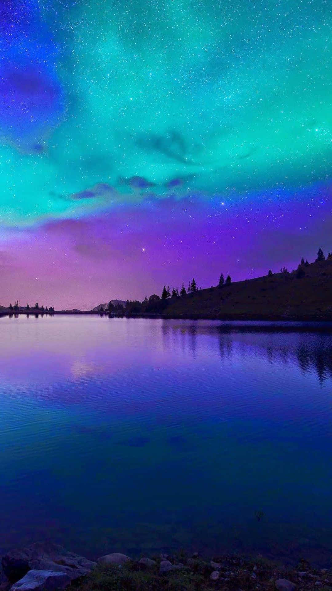 與眾不同的手機——iPhone 8 Plus 壁紙 — 寧靜的湖面映照著在遙遠山丘上、繁星點點的紫色和青色天空中舞動的極光。