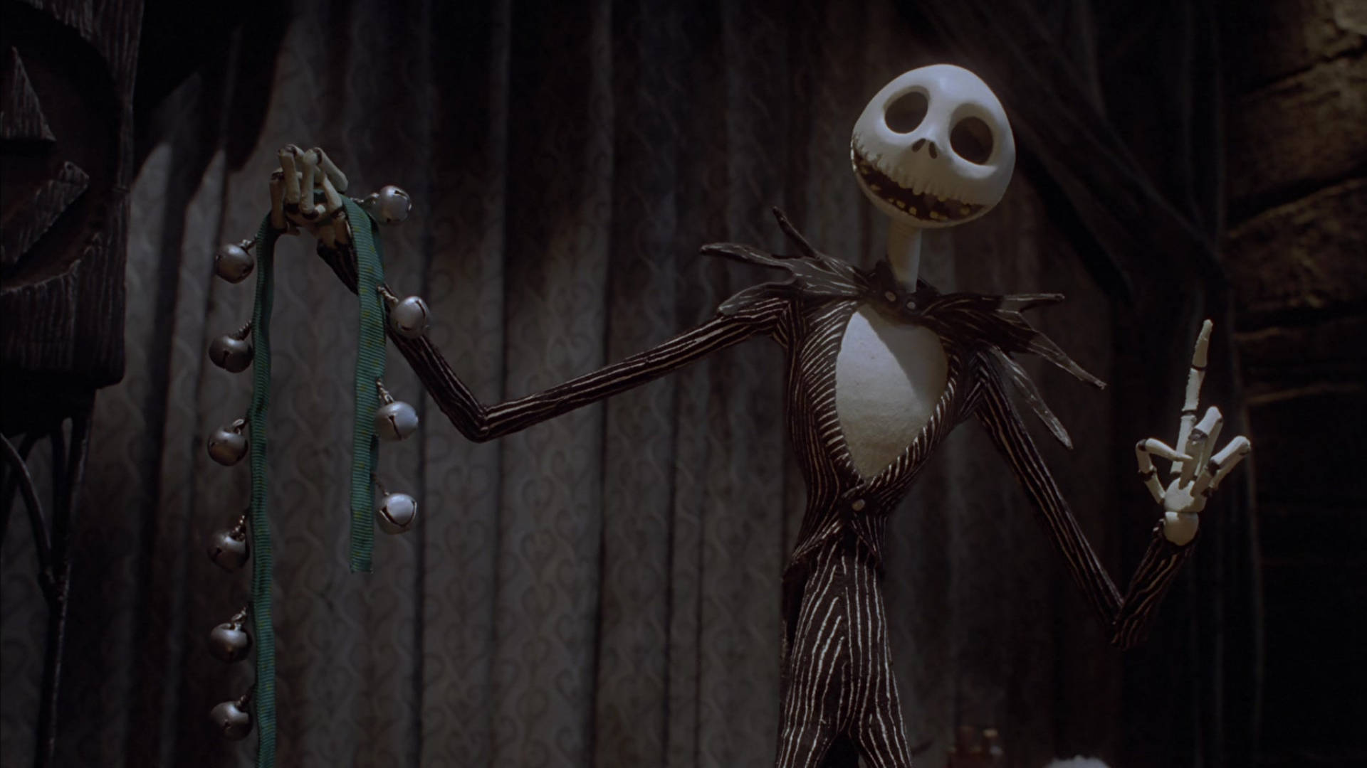 恐怖動圖 桌布 壁紙 — Jack Skellington 穿著其標誌性的條紋西裝，在深色窗簾背景下手持一串銀鈴。