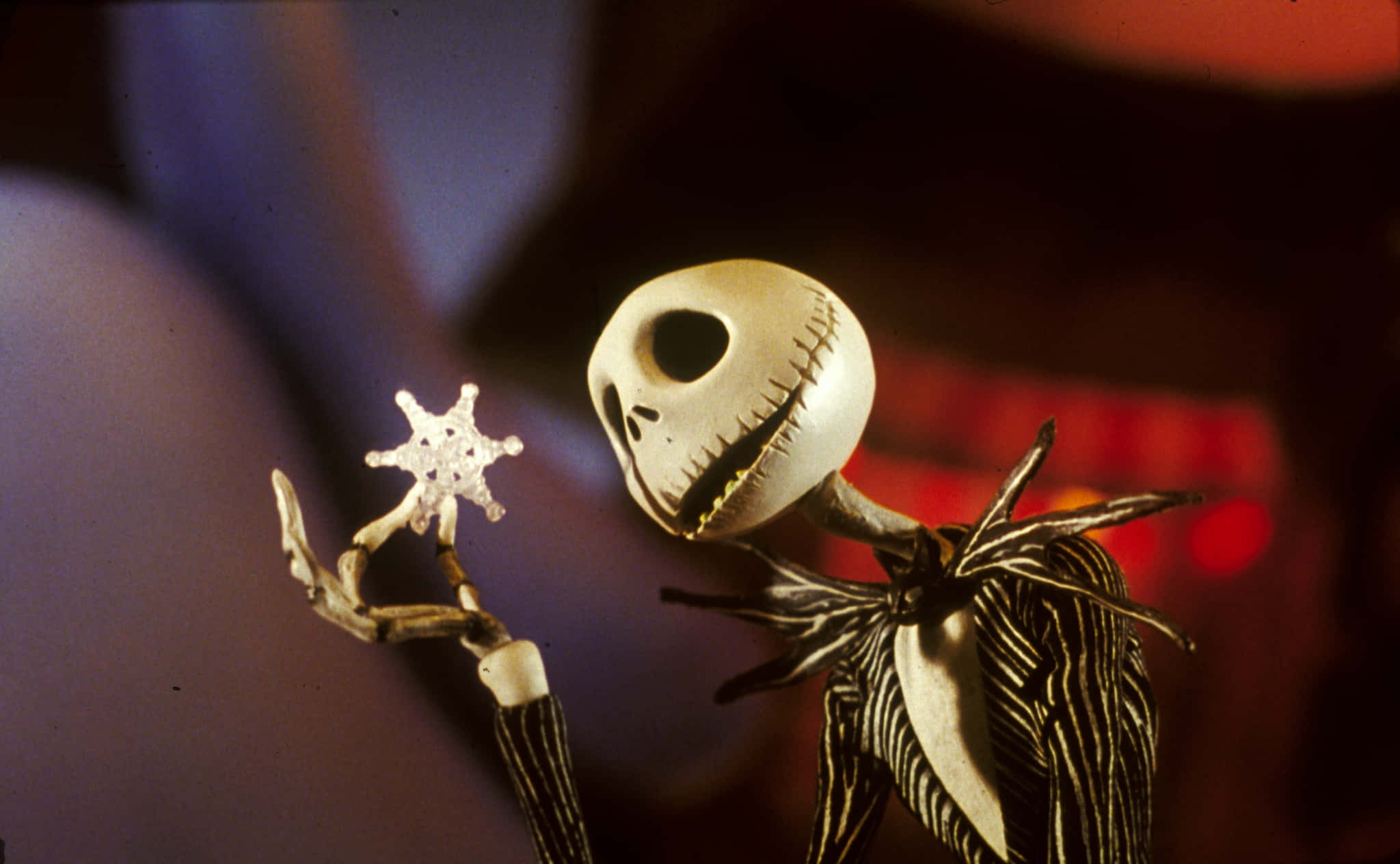 傑克·史克林頓 桌布 壁紙 — Jack Skellington 在昏暗多彩的背景中手持發光雪花。