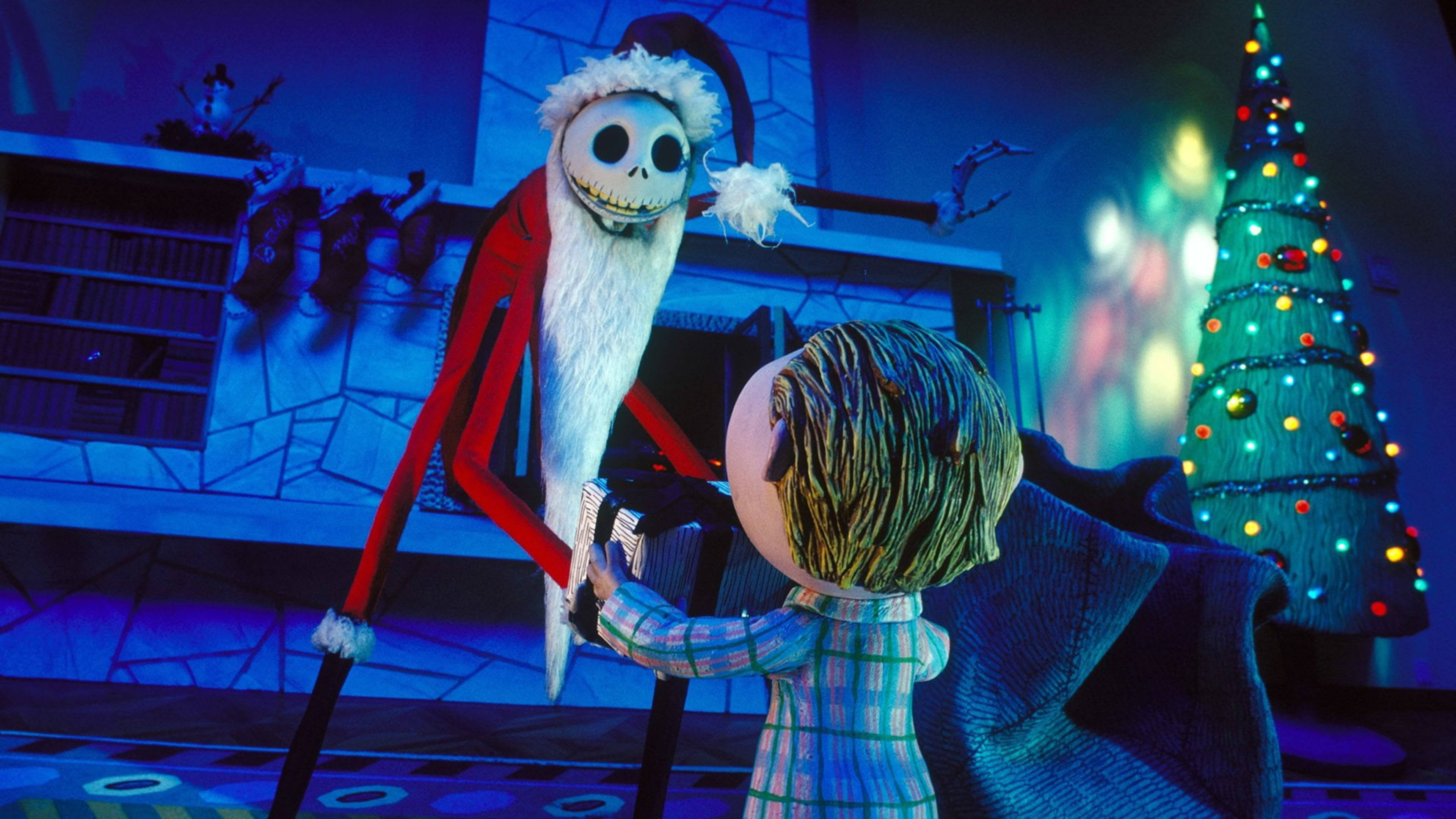 Jack Skellington 桌布 壁紙 — Jack Skellington 穿著聖誕老人套裝，在一個裝飾著樹的節日而詭異的假日房間裡，將禮物遞給一個孩子。