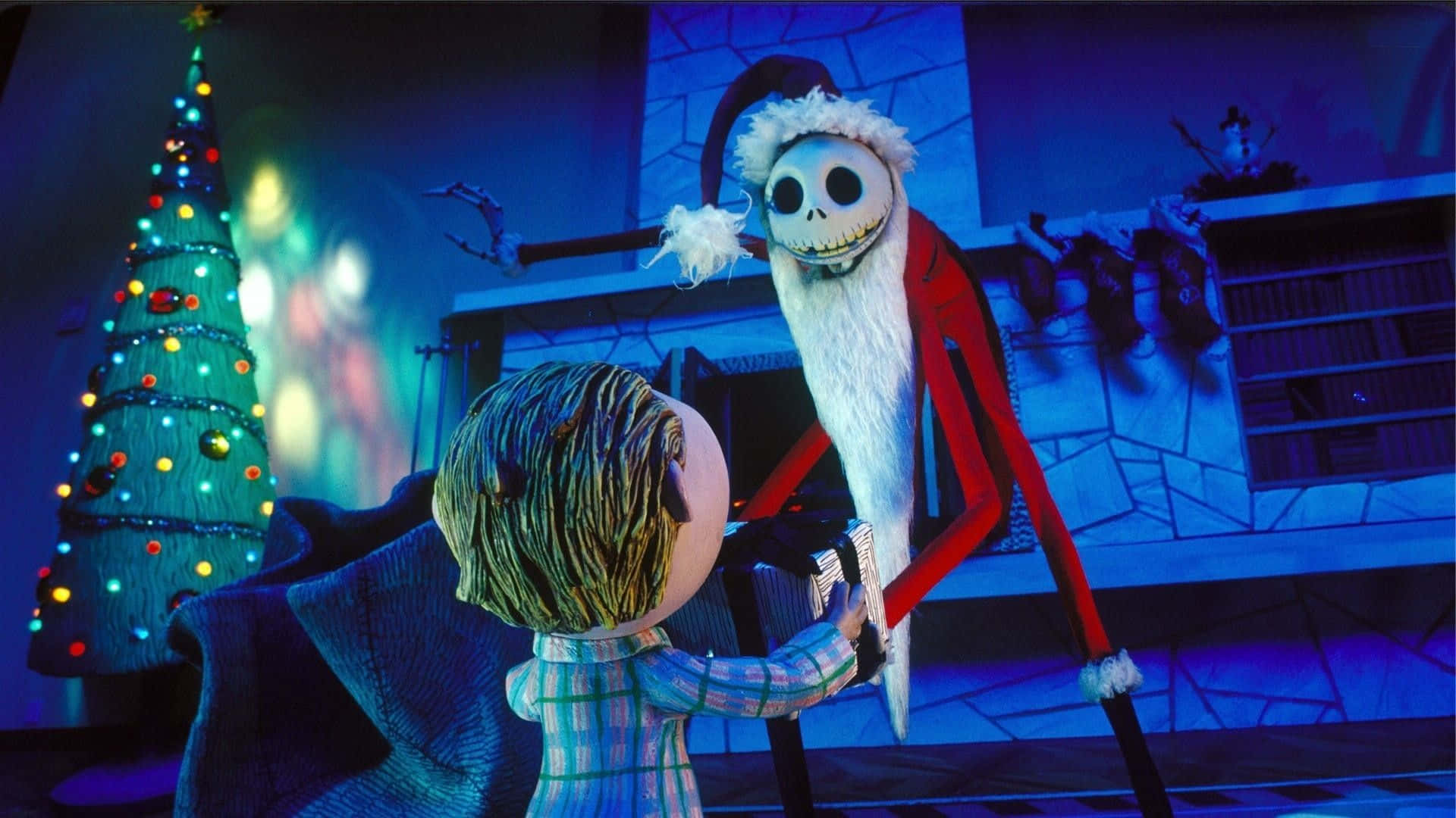 聖誕夜驚魂 桌布 壁紙 — Jack Skellington 穿著紅色聖誕老人服裝，白色毛邊，在藍色燈光的房間裡，旁邊是裝飾好的聖誕樹，牽著一個孩子的手。