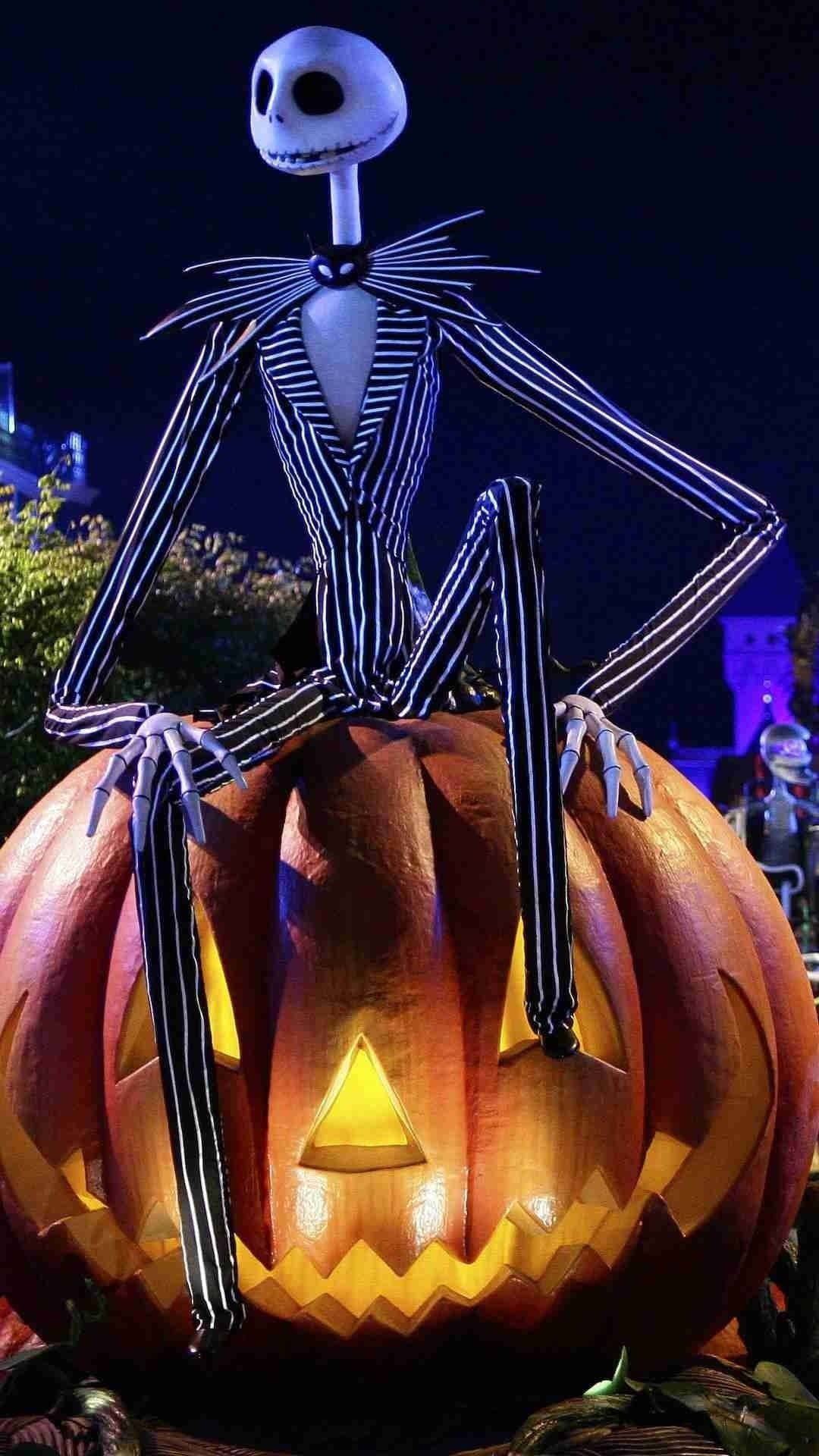 聖誕夜驚魂 桌布 壁紙 — Jack Skellington 夜晚坐在發光的南瓜上，背景是深藍色的天空和節日燈飾。
