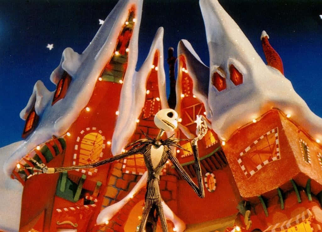 Jack Skellington 在夜晚的雪覆蓋薑餅屋前。 — 聖誕夜驚魂 GIF 壁紙