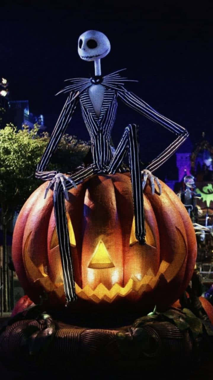 萬聖節美學 桌布 壁紙 — Jack Skellington 坐在一個發光的南瓜燈上，背景是黑暗的夜晚萬聖節場景，伴有節日燈光。