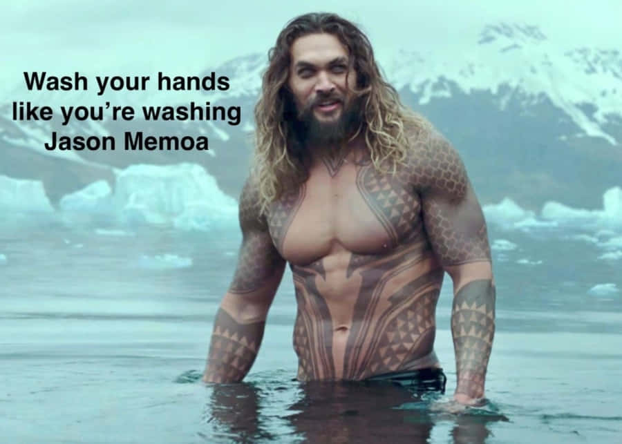 meme 桌布 壁紙 — Jason Momoa 站在冰水中，身後是積雪的山峰，展示著精細的刺青和長髮。