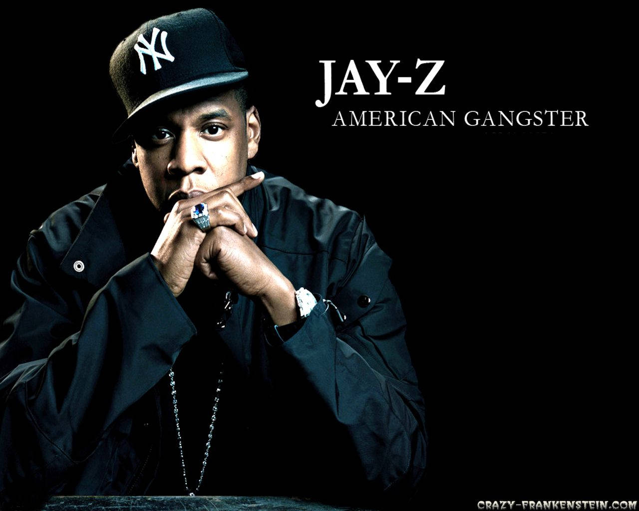 Jay-z 桌布 壁紙 — Jay-Z 凝視著，雙手緊握在嘴邊，戴著NY帽子和黑色外套，背景為黑色。