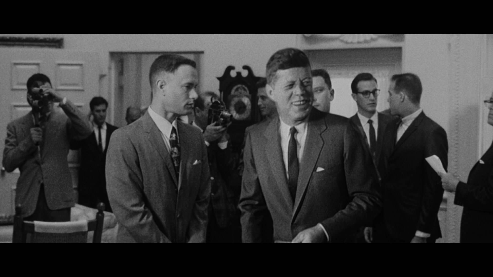 forrest 桌布 壁紙 — JFK 在正式室內環境中被記者及攝影師包圍，溫暖微笑的黑白照片。