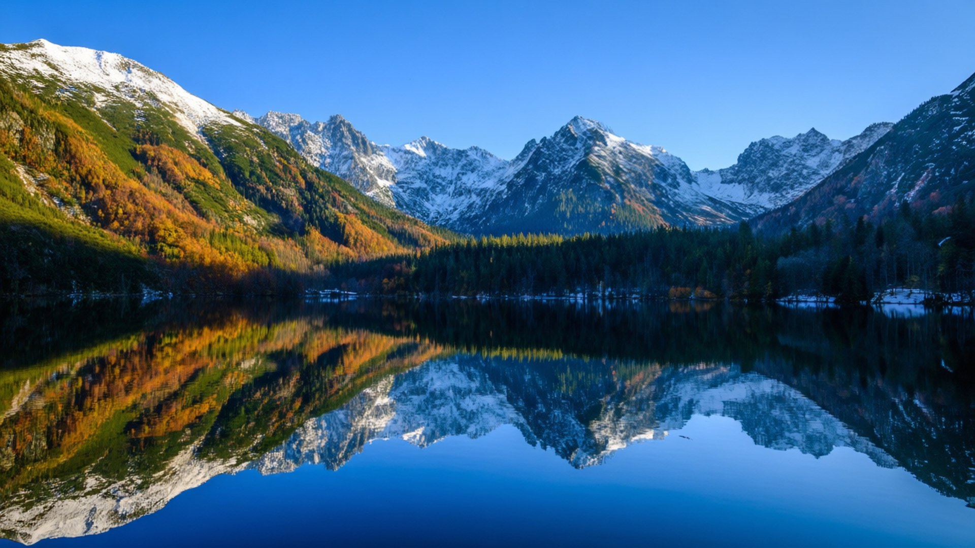 Morskie Oko Lake Reflection 壁紙 — 積雪的山峰與秋日森林完美倒映在平靜的藍色湖面上，天空晴朗。