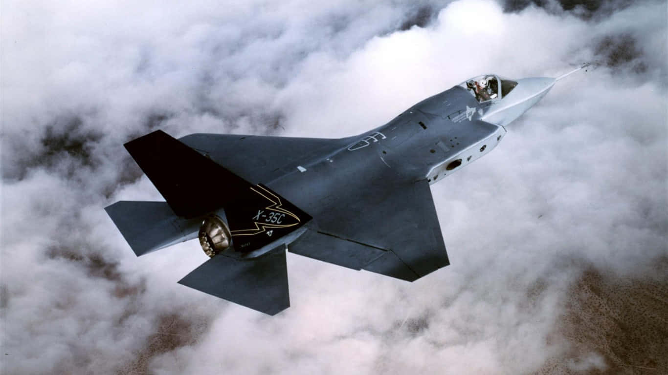 灰色X-35C戰鬥機在厚雲上方飛行，飛行員可見。 — 1366X768 壁紙