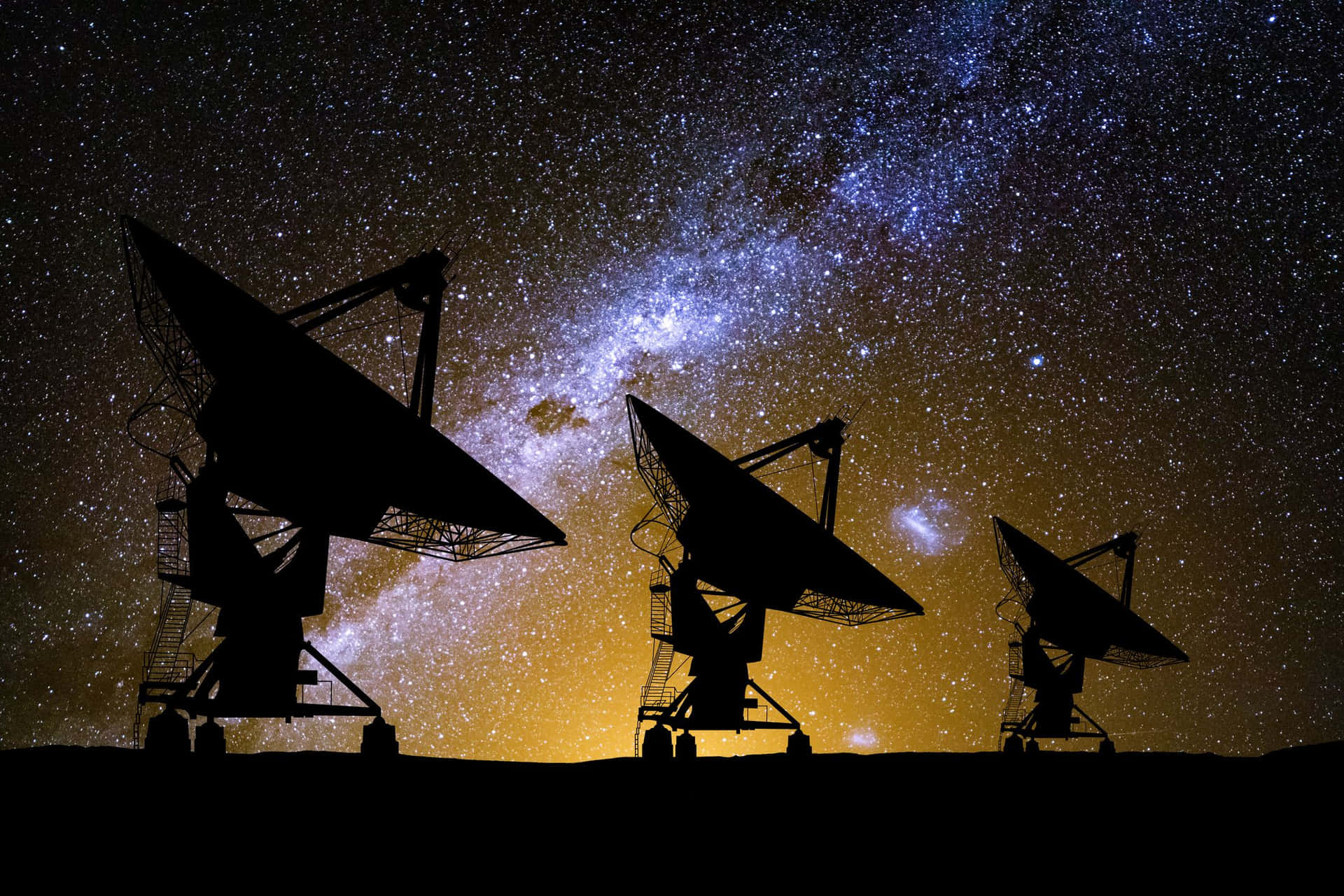  壁紙 — 剪影的電波望遠鏡矗立在充滿活力的星空下，銀河系閃耀著鮮明的藍色和黃色。