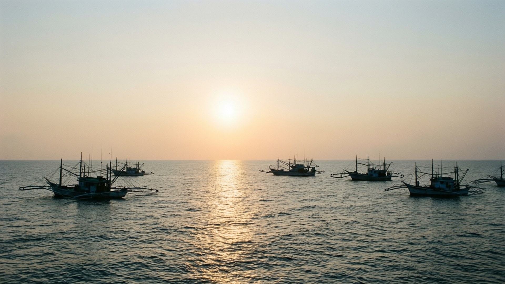Manila Coastline Sunrise 壁紙 — 剪影的漁船在海洋上平靜漂浮，夕陽散發溫暖的金色光芒。