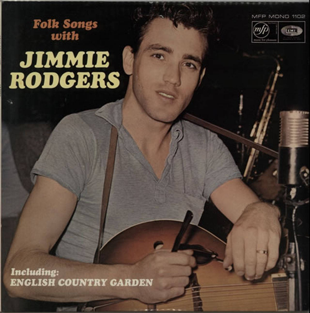guitar player 桌布 壁紙 — Jimmie Rodgers 在黑暗的錄音室背景下，拿著吉他站在復古麥克風旁，並附有專輯文字。