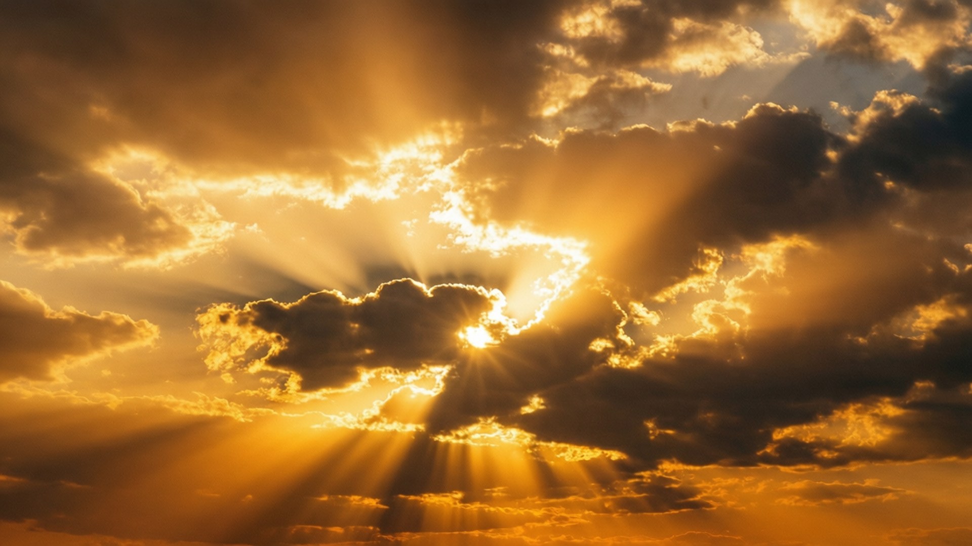 Radiant Golden Rays 壁紙 — 金色的陽光穿透戲劇性的烏雲，在火紅的日落天空中。