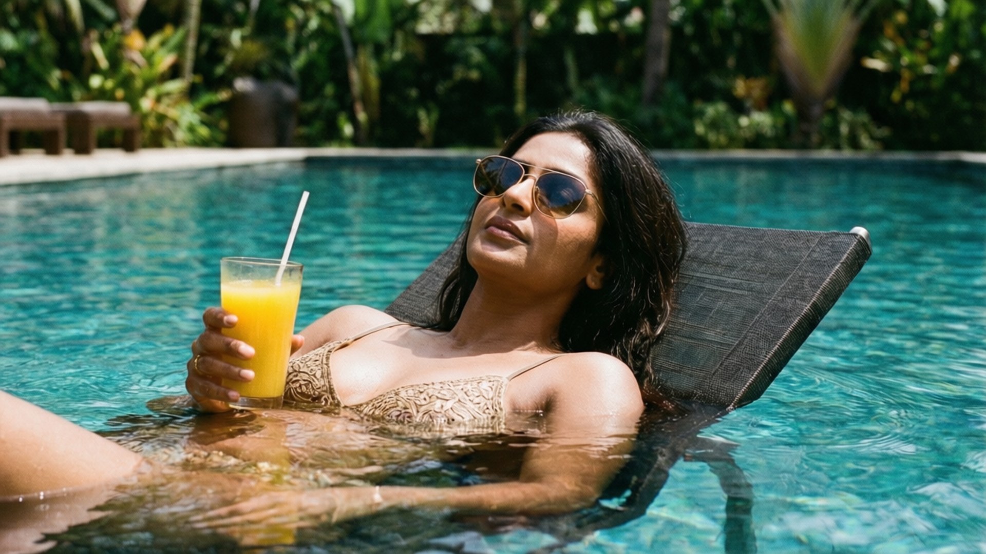 Poolside Refreshment 壁紙 — 一位身穿金色泳衣的女性在藍綠色泳池中放鬆，手持黃色飲料，戴著太陽眼鏡。