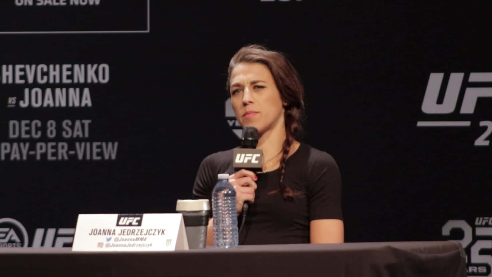professional 桌布 壁紙 — Joanna Jedrzejczyk 在UFC記者會上發言，桌上放著麥克風和水瓶。