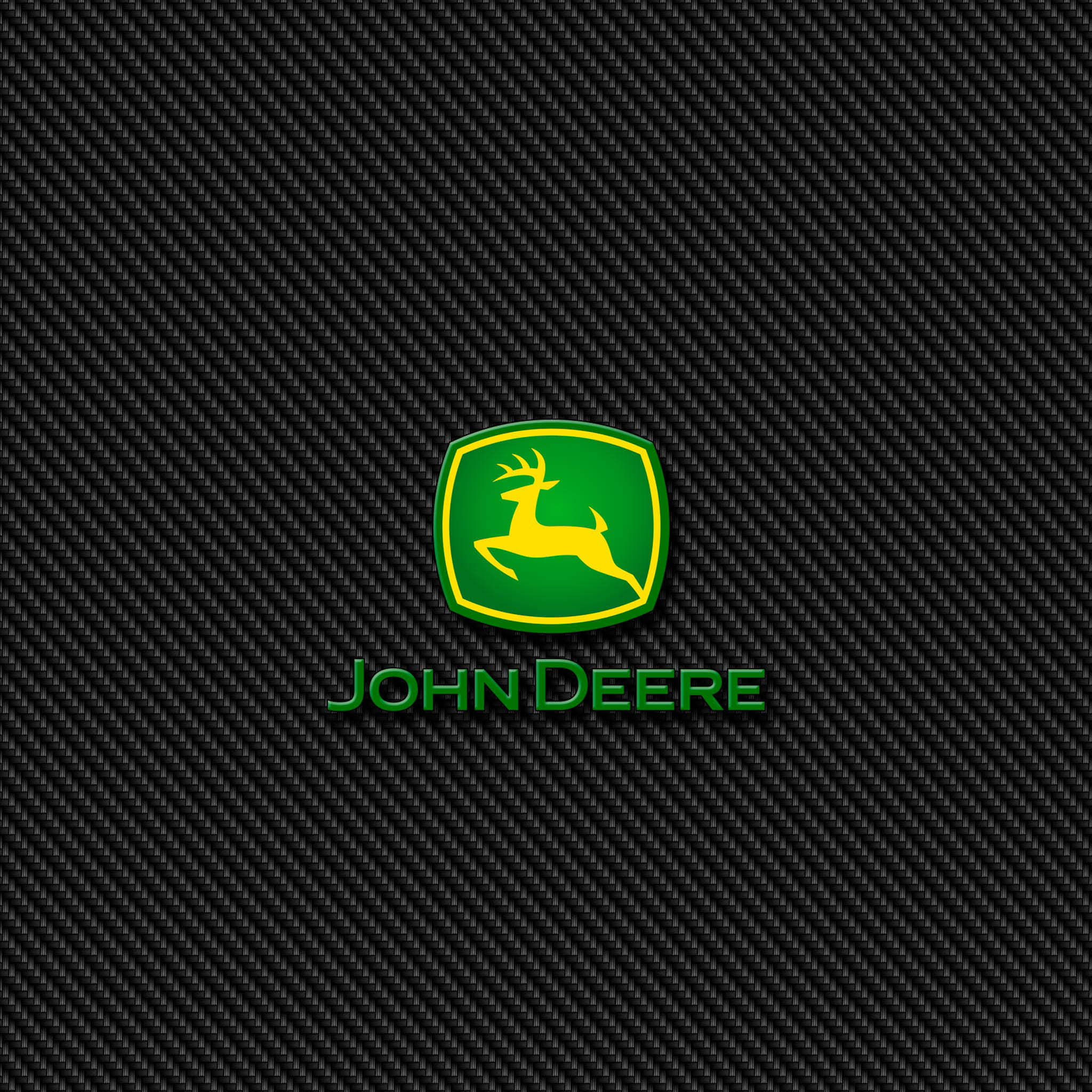 約翰迪爾 桌布 壁紙 — John Deere 標誌，綠色盾牌上有一隻黃色鹿，置於黑色碳纖維紋理背景中央。