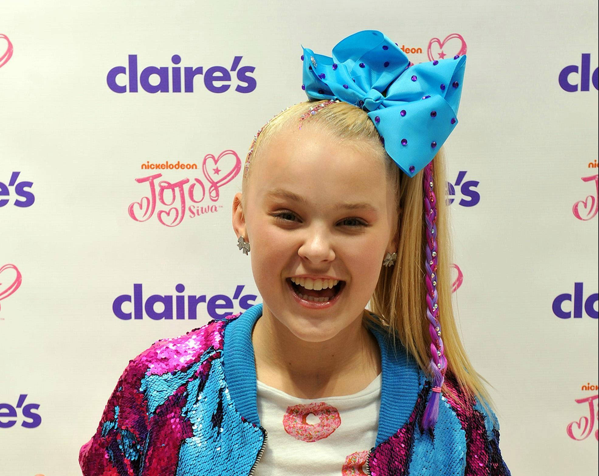 Jojo Siwa 桌布 壁紙 — JoJo Siwa 在 Claire's 活動中戴著巨大的藍色蝴蝶結和閃亮外套，洋溢著喜悅。