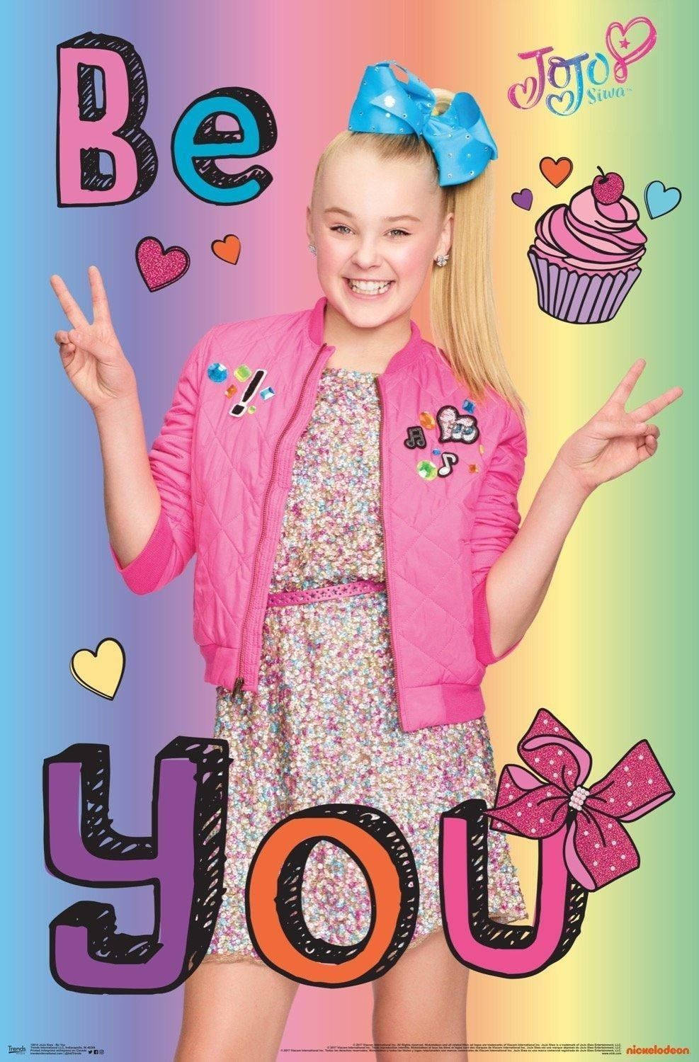 Famous 桌布 壁紙 — Jojo Siwa 穿著粉紅色外套，在彩虹背景中帶著心形和杯子蛋糕燦爛微笑。